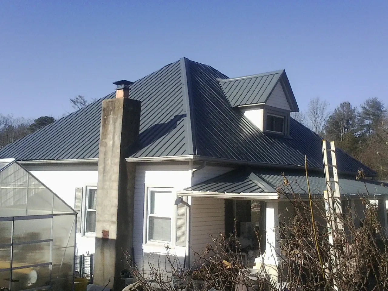 Dark blue standing seam metal roof on a white farmhouse with dormer — Slate & Tile Roof Repair by Roofing Brothers in Reynoldsburg