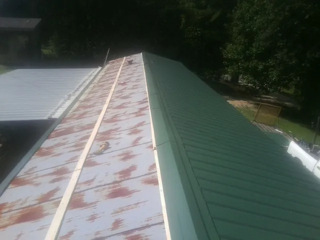 Old rusted panels beside newly installed green metal roofing — Wind Damage Roof Repair by Roofing Brothers in Reynoldsburg
