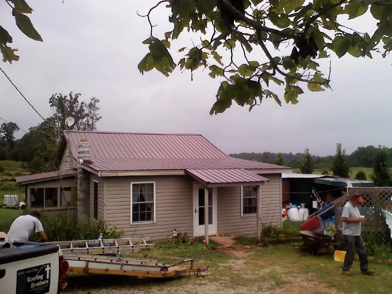 Crew finishing a mauve metal roof on a small farmhouse in Reynoldsburg