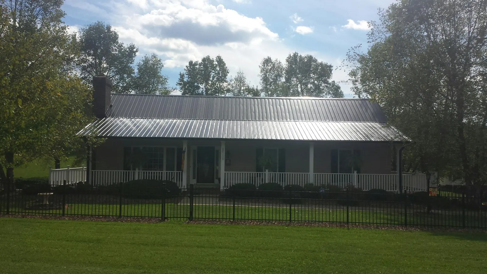 Gray metal roof on a brick ranch with a full width front porch — Gutter Guard Installation work by our crew in Reynoldsburg