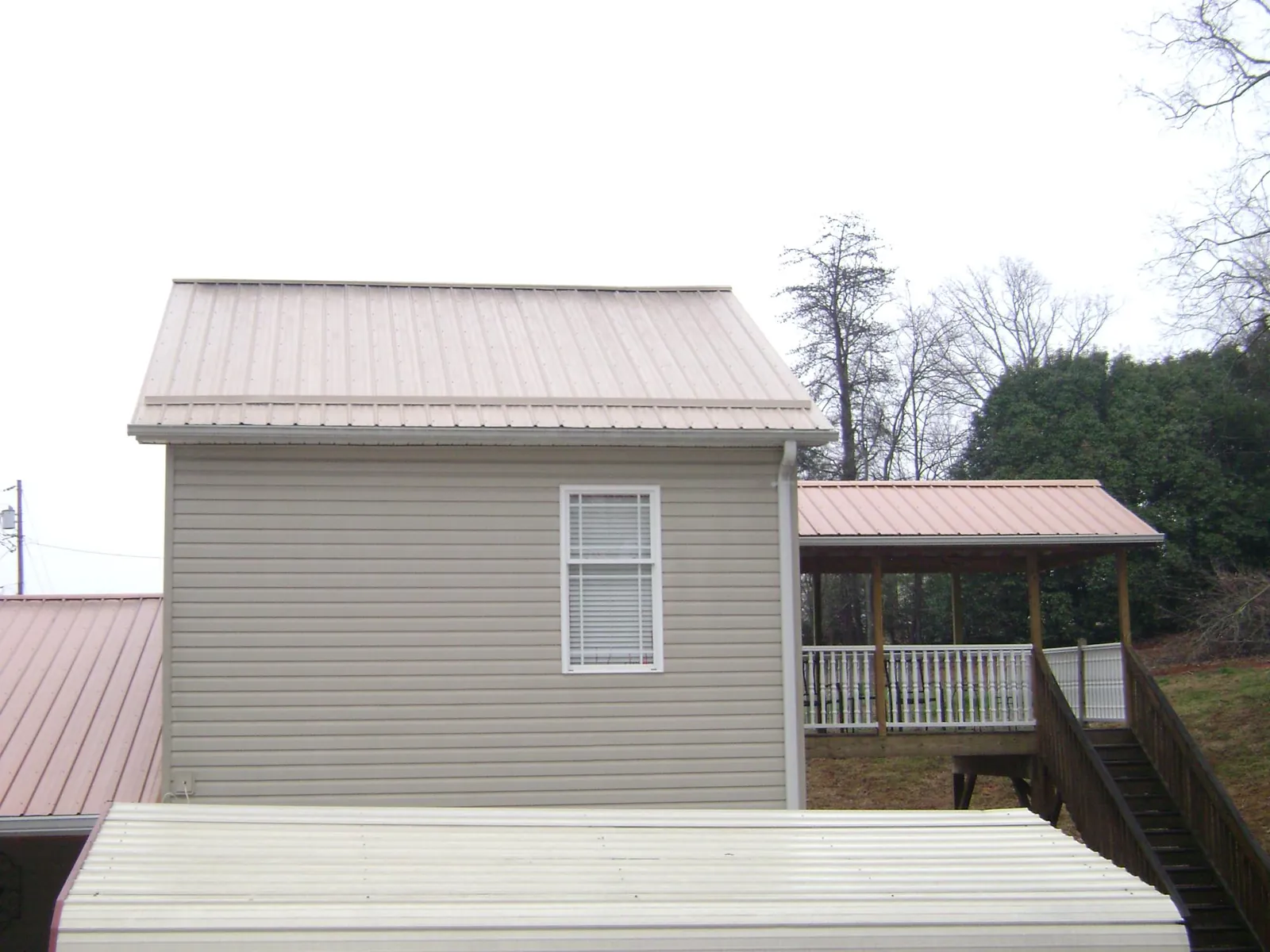 Tan metal roofs on a two story addition and attached porch, from a Roof Replacement job in Reynoldsburg
