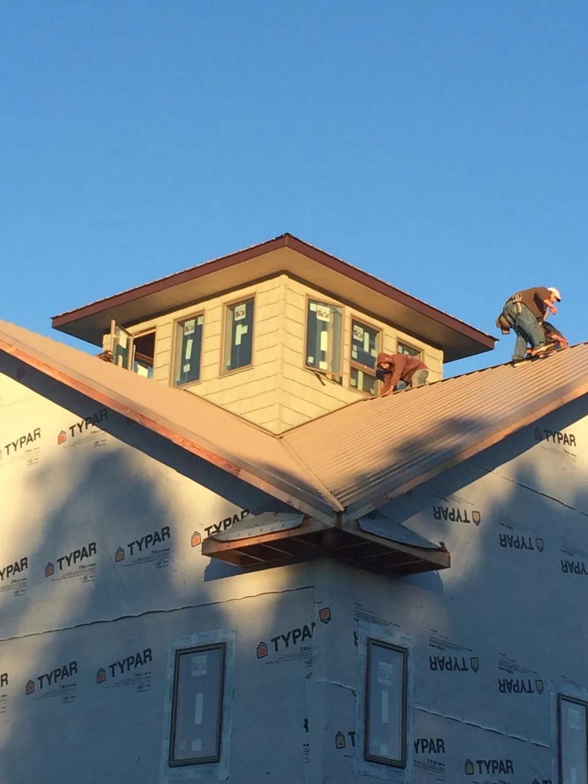 Roofers working around a rooftop cupola on a new metal roof at sunset — Roof Waterproofing in Reynoldsburg by Roofing Brothers